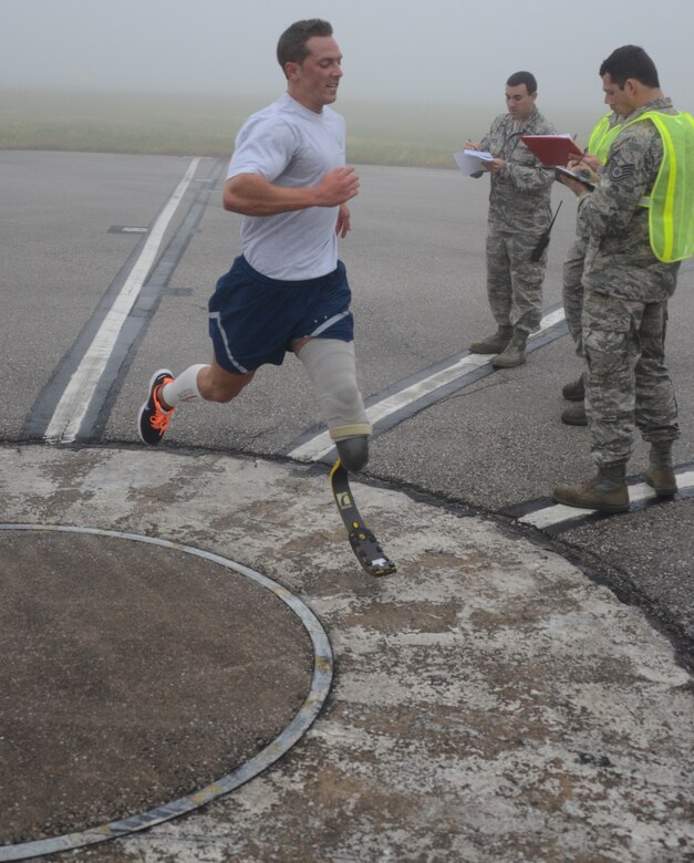 Senior Airman Gideon Connelly crosses the finish line of the PT test after running the closed taxi way in the fog. He finished the 1.5 run in 11:17. Connelly passed the PT test with a score of 94.80 percent. In addition to the run, he accomplished 71 situps in one minute and 90 push ups in a minute to reach that score. (Air National Guard photo by Tech. Sgt. David Speicher/RELEASED)