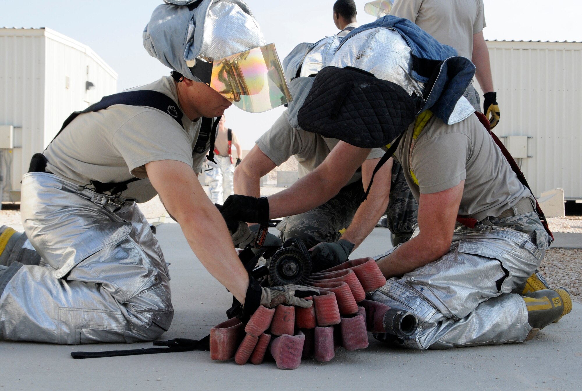 Members of the 379th Expeditionary Civil Engineer Squadron work together to store a fire hose after a fire attack and search and rescue tactics exercise at the 379th Air Expeditionary Wing in Southwest Asia, Dec. 5, 2013. The 379th ECES fire department conducts monthly training to keep crews proficient, safe and ready to handle any fire-related situation. (U.S. Air Force photo/Senior Airman Hannah Landeros)