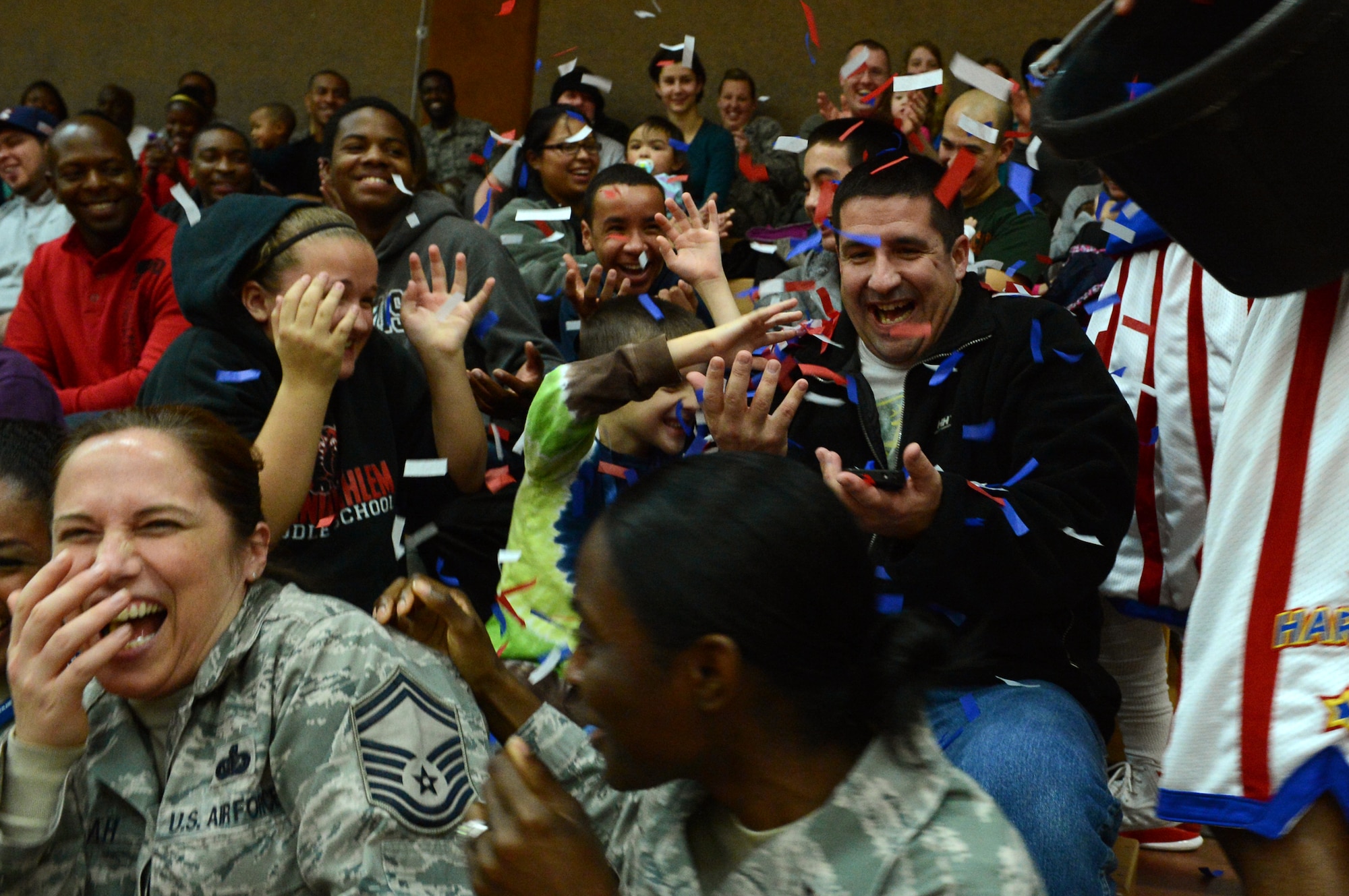 SPANGDAHLEM AIR BASE, Germany --- A member of the Harlem Globetrotters basketball team dumps a bucket of confetti on members of an audience during a complimentary game at the Skelton Memorial Fitness Center Dec. 4, 2013. The team also sprayed water and utilized trick basketballs during the game. (U.S. Air Force photo by Airman 1st Class Kyle Gese / Released)