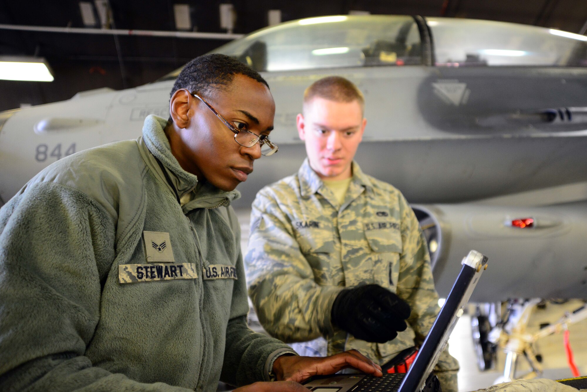 Airman 1st Class Mekai Stewart, left, and Senior Airman Ryan Skarin, 35th Aircraft Maintenance Squadron weapons systems technicians, review technical orders for a job on a U.S. Air Force F-16 Fighting Falcon at Misawa Air Base, Japan, Dec. 6, 2013. The weapons systems crew removed the jet’s center line pylon to install new cover panels that protect the jet from debris and also aid aerodynamics. (U.S. Air Force photo by Senior Airman Derek VanHorn)