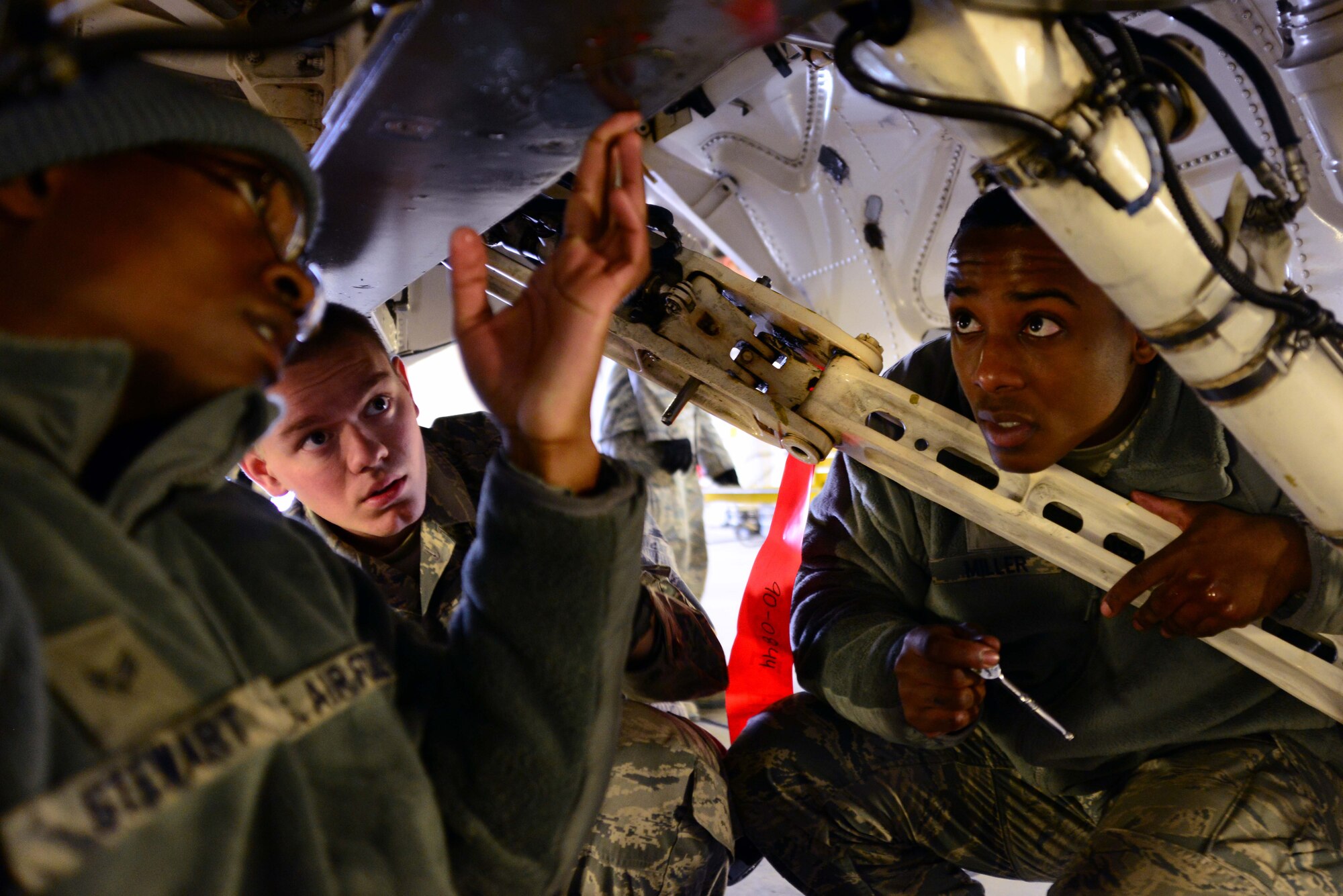From left: Airman 1st Class Mekai Stewart, Senior Airman Ryan Skarin and Senior Airman James Miller, 35th Aircraft Maintenance Squadron weapons systems technicians, remove a center line pylon to replace cover panels on an F-16 Fighting Falcon at Misawa Air Base, Japan, Dec. 6, 2013. The center line pylon connects fuel tanks, bombs and pods to the jet, and is routinely checked for maintenance. (U.S. Air Force photo by Senior Airman Derek VanHorn)