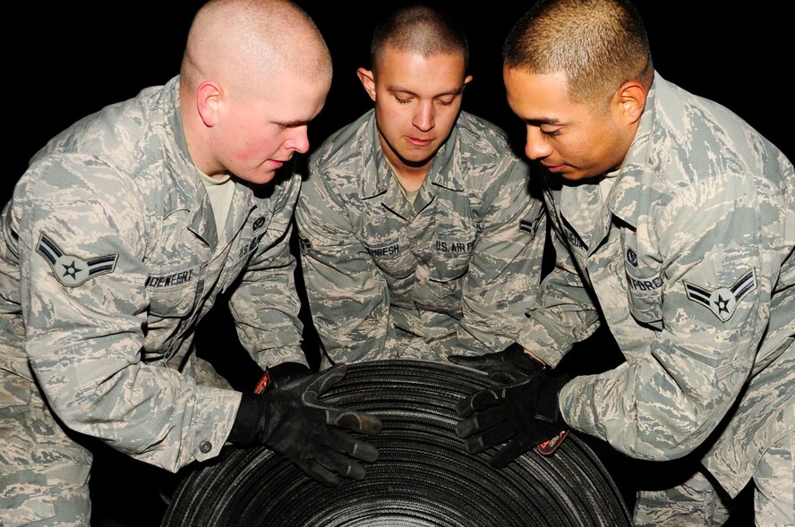 U.S. Air Force Airman 1st Class Isaac Vandeweert, from Harford, N.Y., Spencer Thresh, from Port Orchard, Wash.,  and Airman 1st Class Richard Ojeda III, from Texas, prepare aircraft arresting tape for transport as part of the replacement process on Kadena Air Base, Japan, Dec. 6, 2013. Cutting the old tape allows the barrier maintenance Airmen to roll the tape into groups and easily remove it from the flightline. They are assigned to 18th Civil Engineer Squadron electrical power production section. (U.S. Air Force photo by Staff Sgt. Darnell T. Cannady)