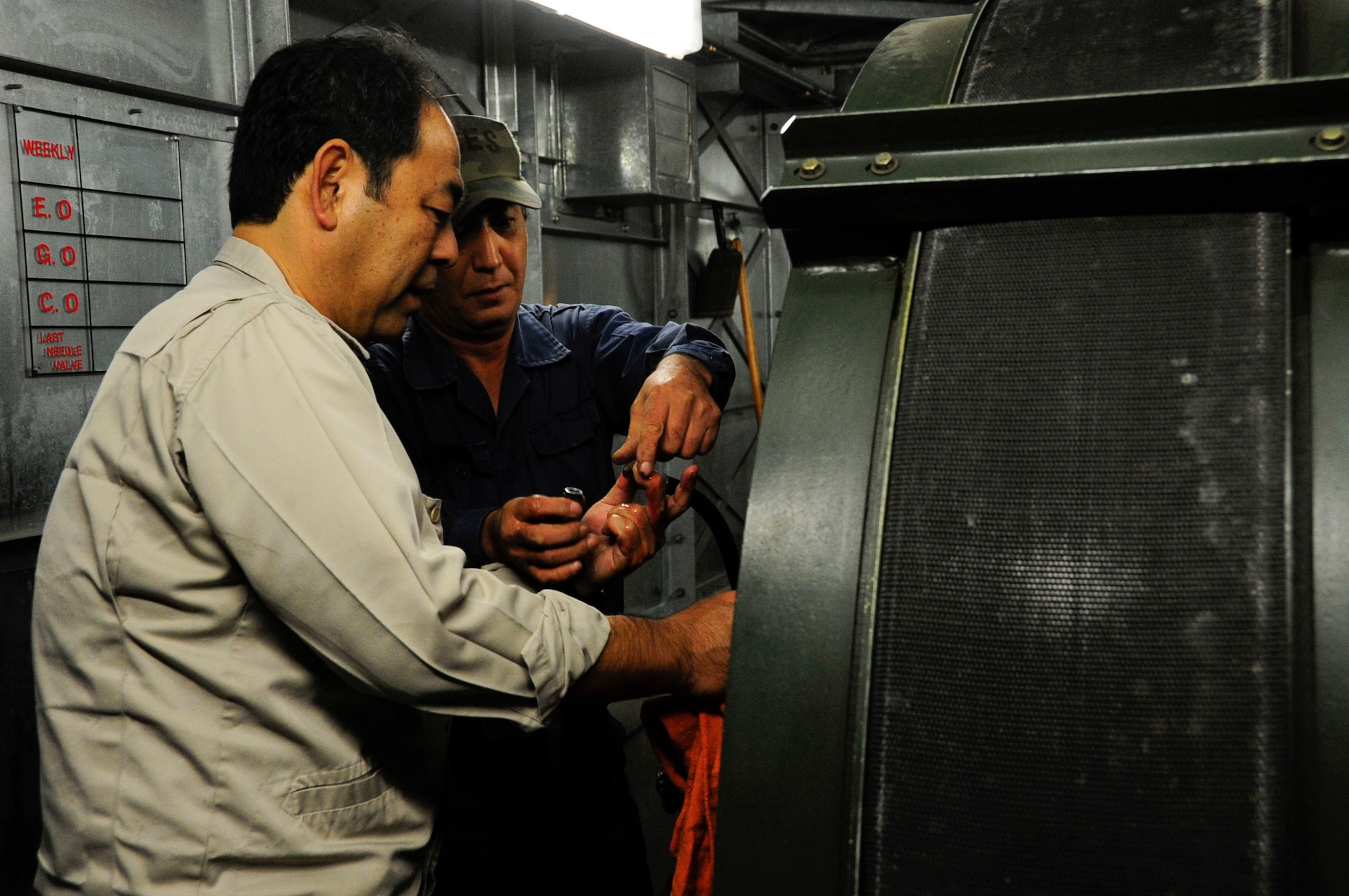 Naoki Nakamura and Oshiro Hidatake, both 18th Civil Engineer Squadron Barrier Maintenance technicians, ensure the arresting tape retracts into the system properly during the replacement of the aircraft arresting tape on Kadena Air Base, Japan, Dec. 6, 2013. The aircraft arresting system safely slows tail hook equipped aircraft in case of an in-flight emergency. (U.S. Air Force photo by Staff Sgt. Darnell T. Cannady)