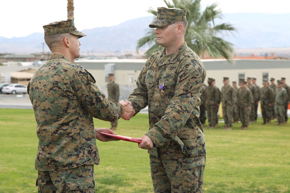 Col. Jay M. Bargeron, commanding officer, 7th Marine Regiment, shakes hands with Sgt. Christopher Travis, intelligence targeting chief, Headquarters company, 7th Marine Regiment, after being awarded a Purple Heart medal at Lance Cpl. Torrey L. Gray Field Nov. 27, 2013.