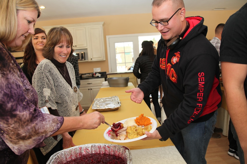 Volunteers Meredith Plummer, left, and Marsha Cole top off Pfc. James Coleman's plate with cranberry sauce during Roughley Manor Bed and Breakfast's fifth annual Thanksgiving dinner for Combat Center personnel in Twentynine Palms. The Plant City, Fla., native was among 100 Marine Corps Communication-Electronics School students treated to a traditional Thanksgiving meal on the holiday. (Official USMC photo by Kelly O'Sullivan/Released)