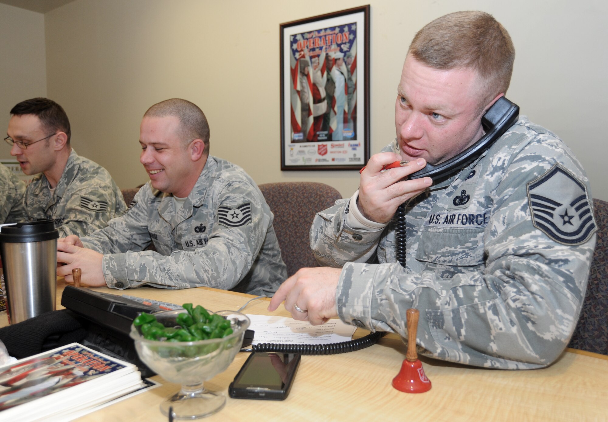 Oregon Air National Guard Master Sgt. Christopher Rich, 142nd Fighter Wing Security Forces Squadron, (right) takes a donation from a caller during the Operation Santa Claus telethon held at KPAM radio in Portland, Ore., Dec. 6, 2013. The 142nd Fighter Wing volunteers helped raise over 47,000 dollars during the final day of The Salvation Army fund raising event, which helps support veterans of Oregon and Southwest Washington. (Air National Guard photo by Tech. Sgt. John Hughel, 142nd Fighter Wing Public Affairs/Released)