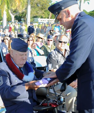 Col. Johnny Roscoe, 15th Wing commander, presents Master Sgt. (ret.) Kenneth Ford a folded flag During the Hickam Field Attack Remembrance Ceremony at Hickam Field on Dec. 7, 2013. Ford was gifted the flag in recognition of his selfless service during the 1941 attack that claimed the lives of 190 Airmen and civilians. Ford, 88, was only 16 years-old at the time of the attacks and lied about his age to be able to enlist in the service at only 15. Ford was one of four survivors to attend the ceremony, which paid tribute to the fallen men and women as well as the survivors and their family members. (U.S. Air Force photo/Staff Sgt. Terri Paden)