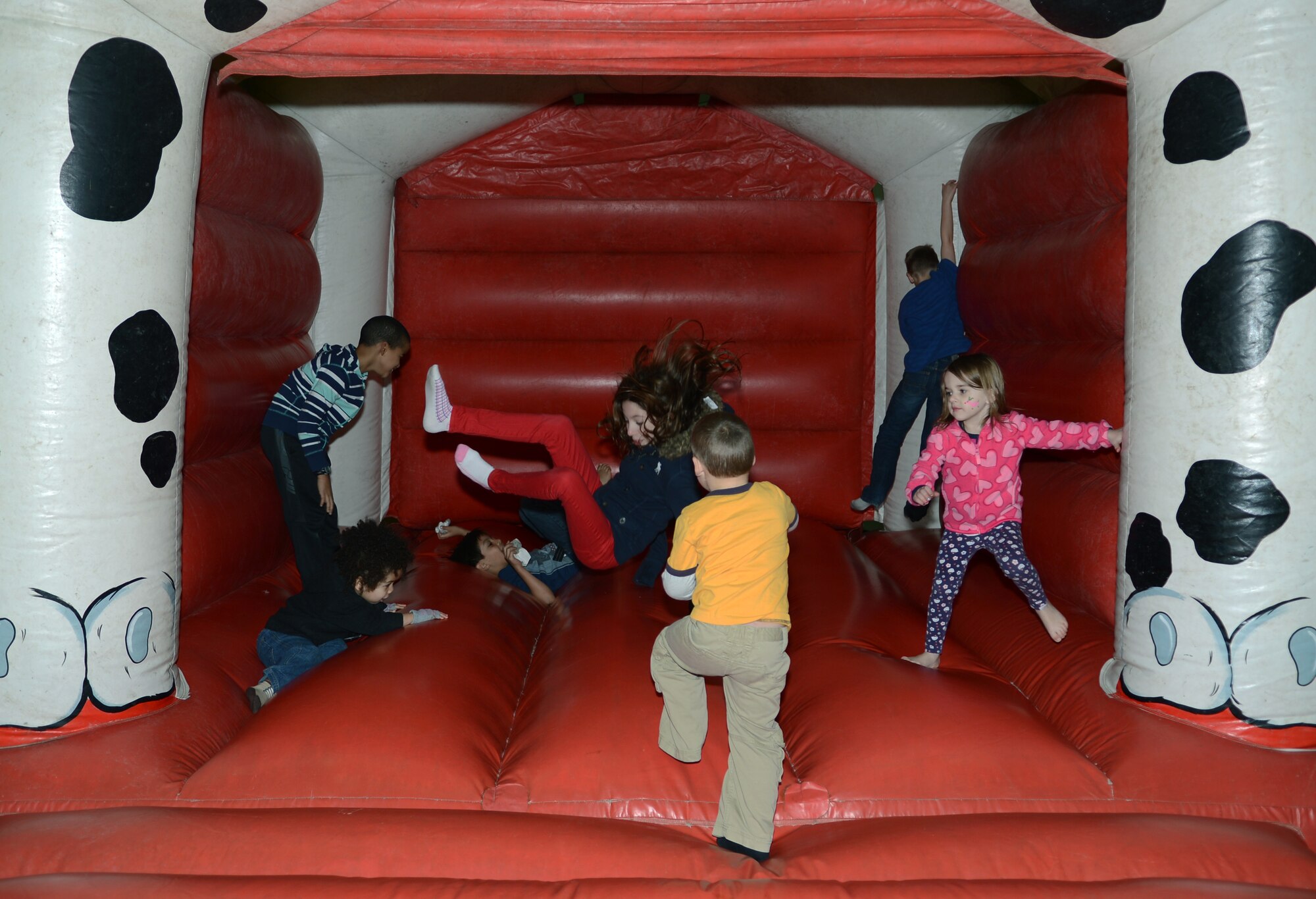 Team Mildenhall children play in a bounce-house during a children’s Christmas celebration Dec. 7, 2013, in hanger 803 on RAF Mildenhall, England. Santa, along with his elf helpers, arrived on a KC-135 Stratotanker and greeted children. Santa’s arrival was followed by many activities to include cookie decorating, bouncy castles, face painting and coloring. (U.S. Air Force photo by Airman 1st Class Dillon Johnston/Released)