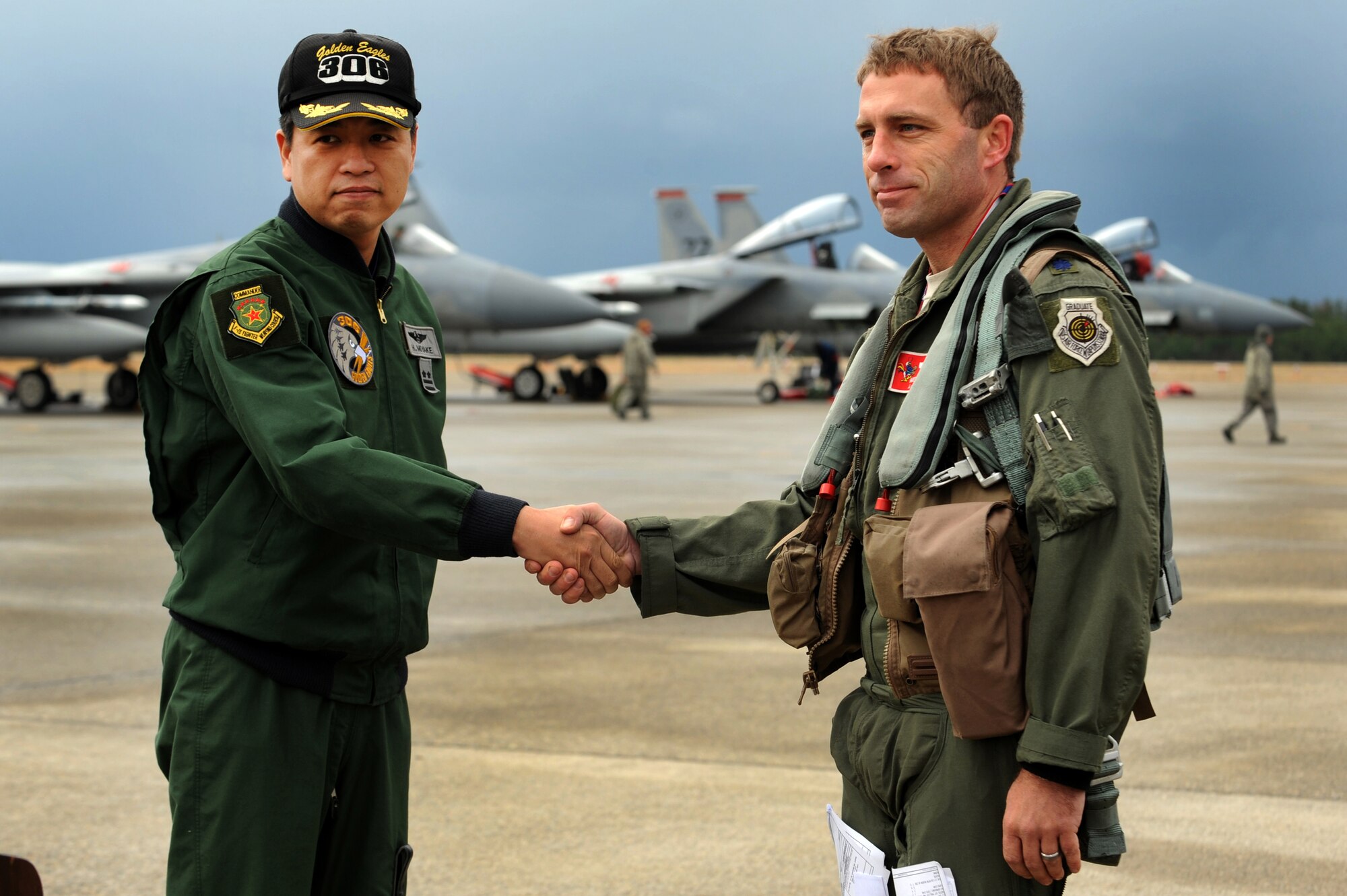 Japanese Air Self Defense Force Lt. Col. Miyake Hideaki, 306th Tactical Fighter Squadron commander, and U.S. Air Force Lt. Col. Morris Fontenot, 67th Fighter Squadron commander, shake hands during a press conference on Komatsu Air Base, Japan, Dec. 7, 2013. Both squadrons will participate in a week-long bilateral Aviation Training Relocation Program hosted by the JASDF 6th Wing. The program emphasizes interoperability training between U.S. and Japanese forces, while promoting operational readiness. (U.S. Air Force photo by Staff Sgt. Amber E. N. Jacobs)