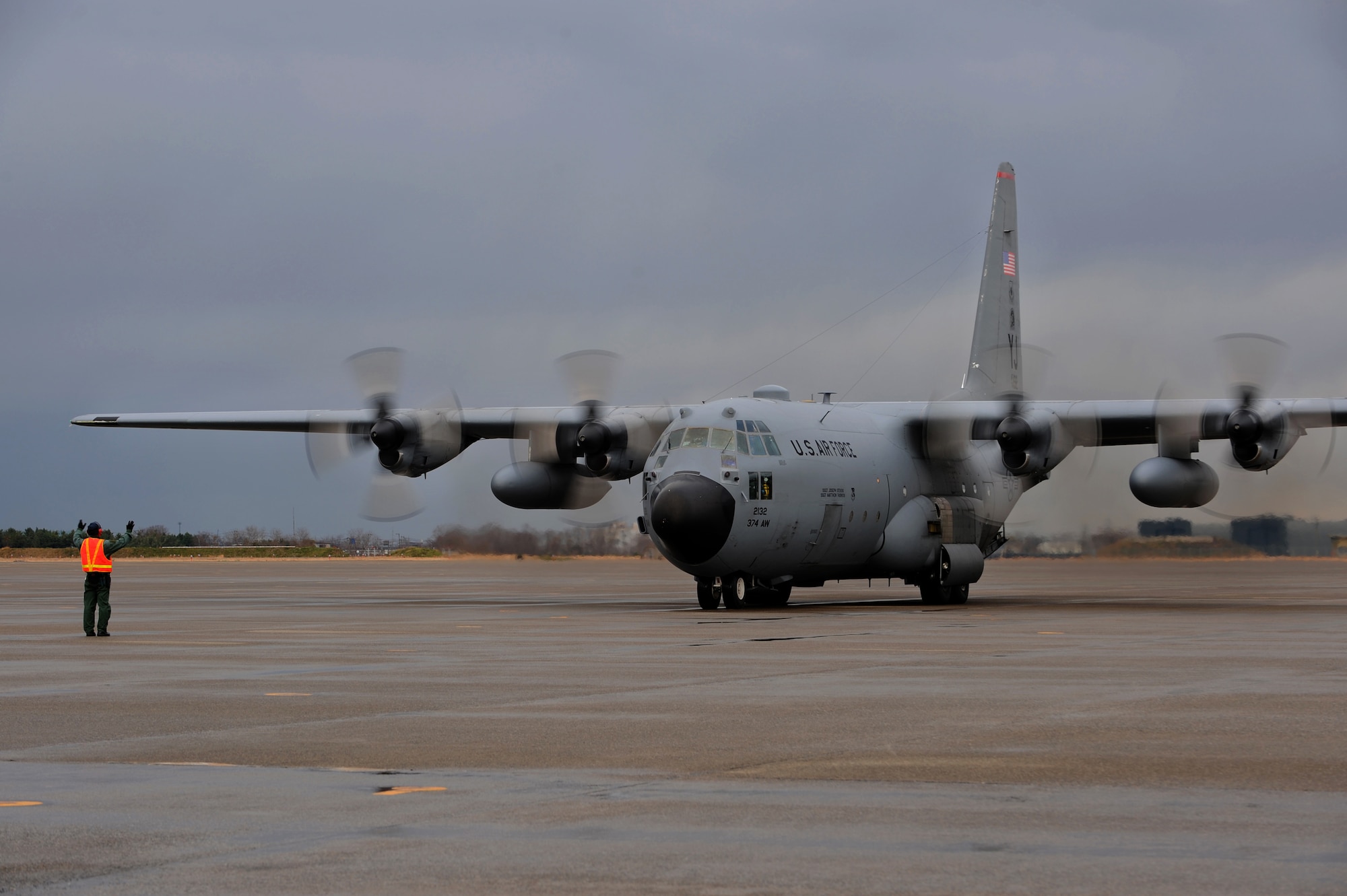 A member of the Japanese Air Self Defense Force marshals a U.S. Air Force C-130 Hercules aircraft from Kadena Air Force Base, Japan, on Komatsu Air Base, Japan, Dec. 7, 2013. The arrival of the C-130 is part of a week-long Aviation Training Relocation Program hosted by the JASDF 6th Wing. (U.S. Air Force photo by Staff Sgt. Amber E. N. Jacobs)