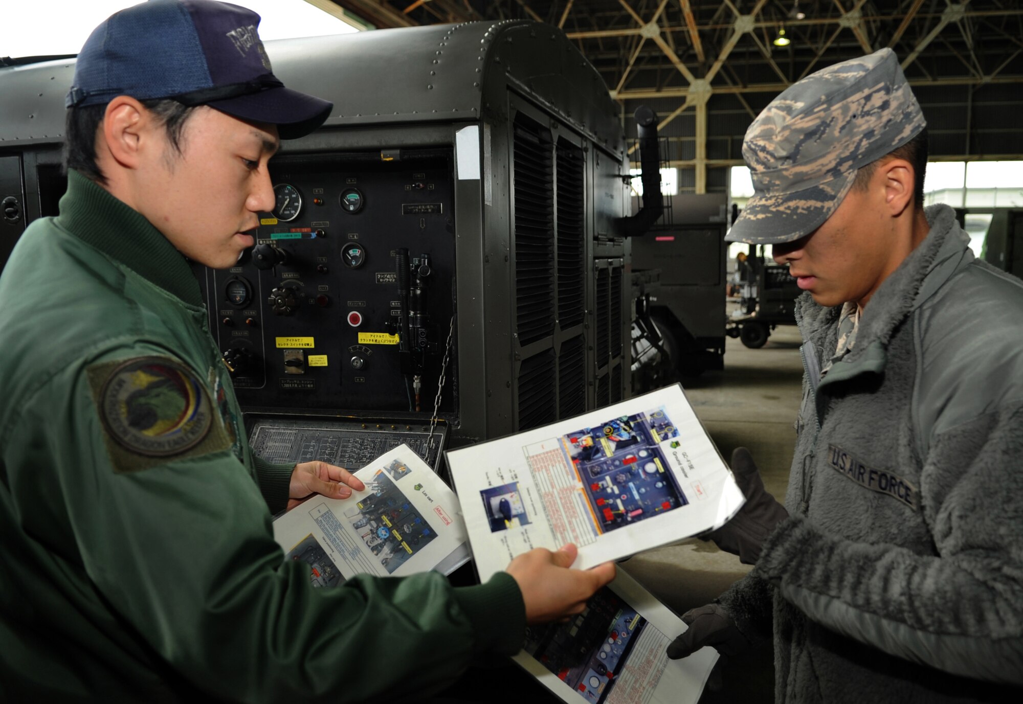 A member of the Japanese Air Self Defense Force gives U.S. Air Force Senior Airman Michael Jacobs, 67th Fighter Squadron crew chief, instructions on how to operate a GC-F15E ground cooler as part of a week-long Aviation Training Relocation Program on Komatsu Air Base, Japan, Dec. 6, 2013. The ATR is a program designed to strengthen bilateral ties with Japanese counterparts as well as local communities. (U.S. Air Force photo by Staff Sgt. Amber E. N. Jacobs)