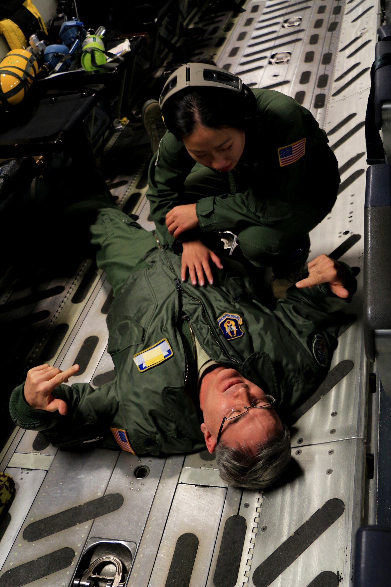 1st Lt. Naomi Warner, 446th Aeromedical Evacuation Squadron flight nurse, aids a Reservist who is simulating a distraught patient during a training flight on a C-17 Globemaster III Dec. 8. The training helps medical Reservists prepare for emergencies that may happen during real-life situations. (U.S. Air Force Reserve photo by Senior Airman Madelyn McCullough)