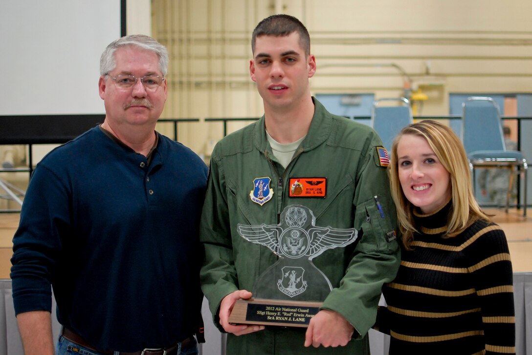 U.S. Air Force Senior Airman Ryan J. Lane of the 169th Airlift Squadron, center, displays the Red Erwin award with family members at the 182nd Airlift Wing, Peoria, Ill., Dec. 8, 2013. Lane competed against 3,000 other Air National Guard candidates to win the Staff Sgt. Henry E. "Red" Erwin Outstanding Enlisted Aircrew Member Airman of the Year Award. He was presented the honor for his outstanding accomplishments, leadership traits that impacted his unit's mission and self-improvement in areas such as education and training. (U.S. Air National Guard photo by Staff Sgt. Lealan C. Buehrer/Released)