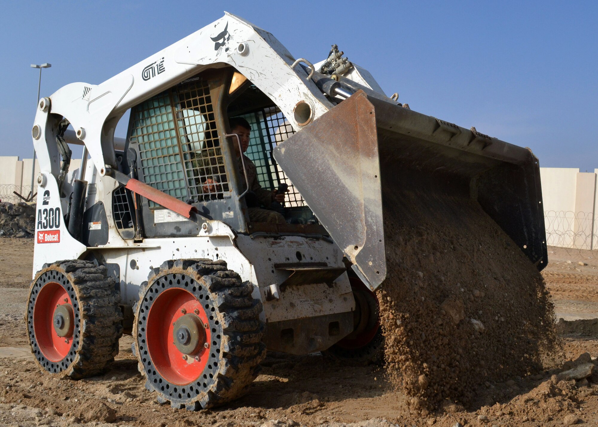 Air Force Staff Sgt. Justin Neufeld, 557th Expeditionary Rapid Engineer Deployable, Heavy Operations Repair Squadron Engineer, operates a Bobcat to prepare the ground area around the new fitness center foundation at an undisclosed location in Southwest Asia, Dec. 5, 2013. The fitness center will provide additional space to support the number of personnel here. (U.S. Air Force photo by Tech. Sgt. Colleen Urban/Released)