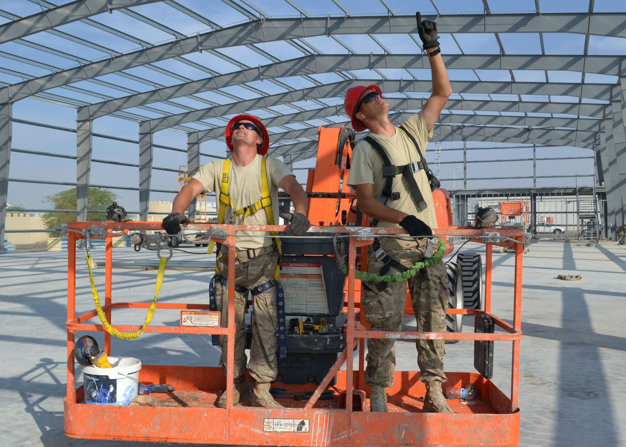 Air Force Staff Sgt. Damon Besimer and Air Force Tech. Sgt. Branden Lane, both assigned to the 557th Expeditionary Rapid Engineer Deployable, Heavy Operations Repair Squadron Engineer, assess their work area prior to being lifted to prepare the fitness center roof for construction at an undisclosed location in Southwest Asia, Dec. 5, 2013. (U.S. Air Force photo by Tech. Sgt. Colleen Urban/Released)