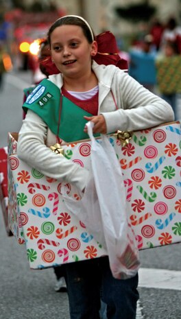 Girl Scout Alyssa Otto, 10, dressed as a present, walks in the annual Camp Kinser Christmas Parade and Tree Lighting Ceremony, Dec. 4, handing out candy along the way.
