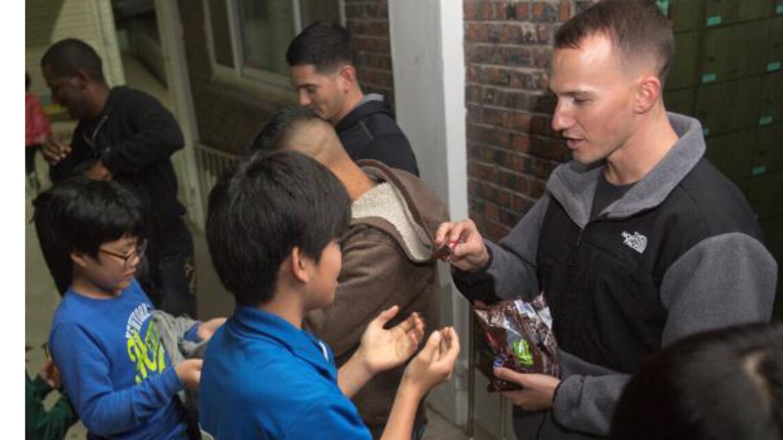 A service member passes out candy to a child from an orphanage in Gunsan during a community relations event, Nov. 5, 2013. Children of the orphanage were excited and tried to get service members to pass out candy before scheduled.