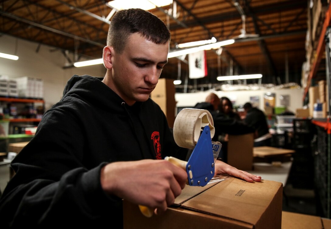 Lance Cpl. Stephen P. Chiasson, intelligence specialist, 15th Marine Expeditionary Unit, assembles a box during a volunteer event at The Angel's Depot in Vista, Calif., Dec. 6. All donations go to improving the quality of life for senior citizens. Chiasson, 19, is from Lafayette, La. (U.S. Marine Corps photo by Cpl. Emmanuel Ramos/Released)