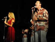 Master Sgt. Lara Murdzia and Senior Airman Devin Rivas Martin, vocalists with the Hana Hou! Rock Band from the Air Force Band of the Pacific, performs a holiday classic song during the 44th Annual Tower Lighting Celebration at Joint Base Pearl Harbor-Hickam, Hawaii, Dec. 6, 2013. The celebration included food and entertainment for all ages, including a visit from Santa, arts and crafts, and live band performances from Hana Hou! Rock Band and singer/ukulele sensation Aidan James. The highlight of the event was the lighting of Freedom Tower by actors Emma Stone and Bill Murray. (U.S. Air Force photo/Staff Sgt. Alex Martinez)