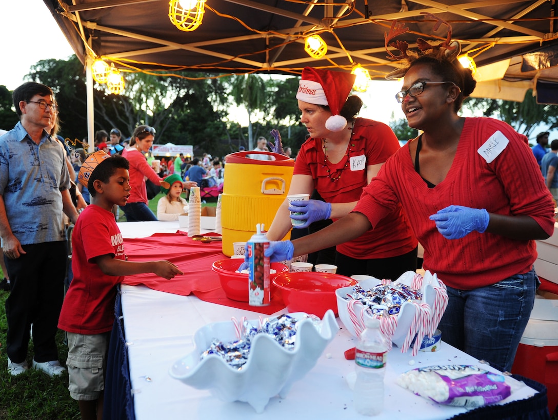 Katie and Marce Bradshaw, mother-and-daughter volunteers with the Hickam Parent-Teacher Association, serve hot chocolate to event attendees during the 44th Annual Tower Lighting Celebration at Joint Base Pearl Harbor-Hickam, Hawaii, Dec. 6, 2013. The celebration included food and entertainment for all ages, including a visit from Santa, arts and crafts, and live band performances from the Hana Hou! Rock Band from the Air Force Band of the Pacific, and singer/ukulele sensation Aidan James.  The highlight of the event was the lighting of Freedom Tower by actors Emma Stone and Bill Murray. (U.S. Air Force photo/Staff Sgt. Alex Martinez)