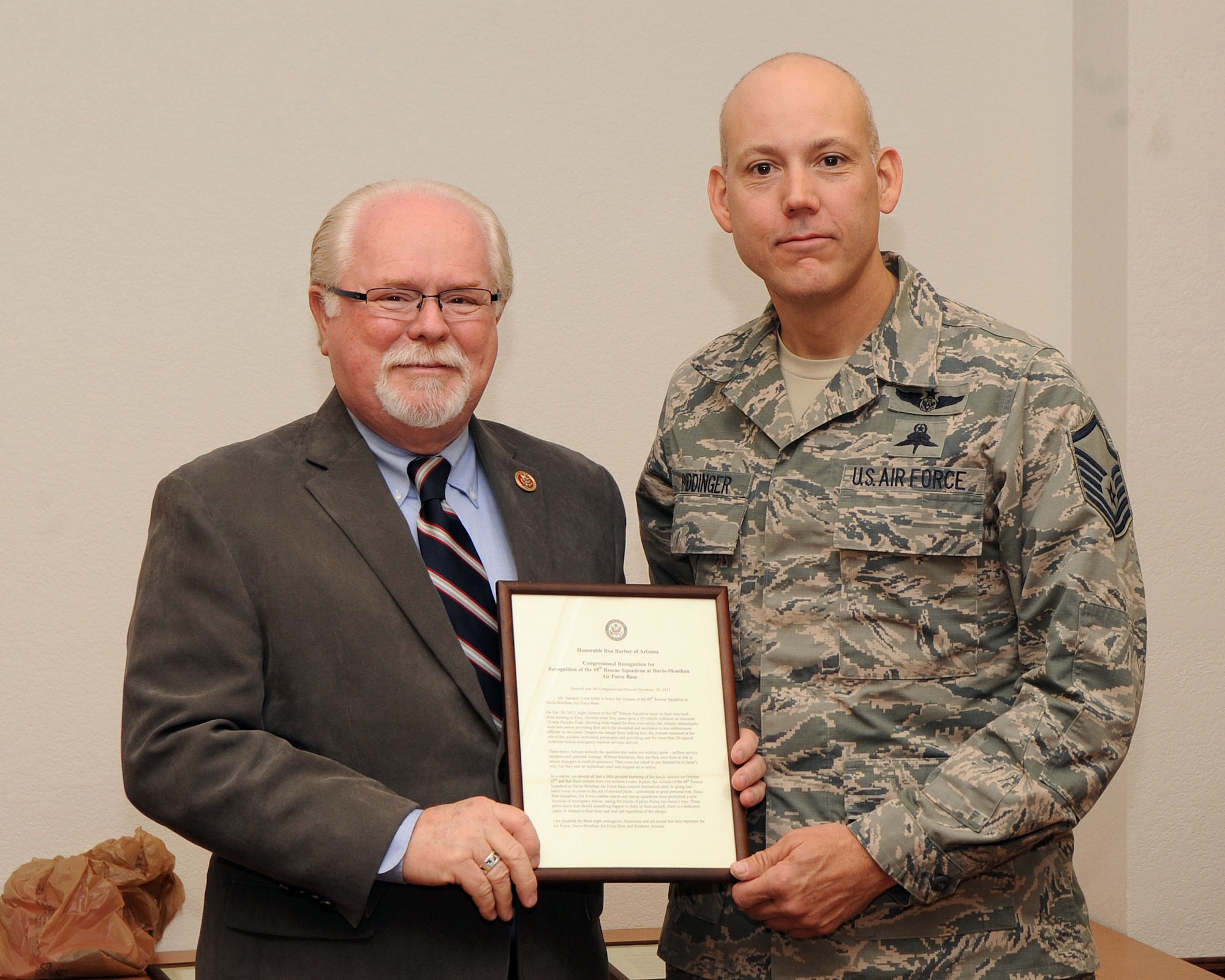 U.S. Air Force Master Sgt. David Biddinger, 48th Rescue Squadron pararescueman, receives a Congressional Recognition certificate from Congressman Ron Barber, 2nd District of Arizona, at Davis-Monthan Air Force Base, Ariz., Dec. 9, 2013. Biddinger was one of eight Airmen who were recognized for their swift actions to help victims of a 19-vehicle crash on Oct. 29. (U.S. Air Force photo by Senior Airman Josh Slavin)