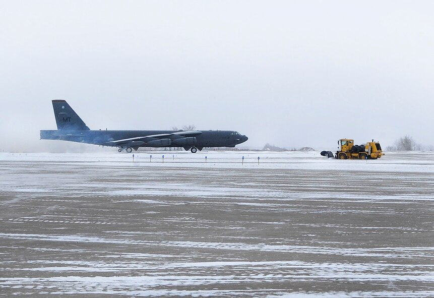 A B-52H Stratofortress taxis for take-off as a snow sweeper clears the opposite runway at Minot Air Force Base, N.D.. Dec. 3. The 5th Civil Engineer Squadron Heavy Equipment Section, employs contractors to operate the sweepers. This partnership plays a critical role in keeping the mission at Minot AFB running smoothly during the winter months, by clearing upwards of 70 inches of snow a year from the runway. (U.S. Air Force photo/Senior Airman Stephanie Sauberan)