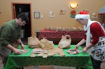 Johnny Adams and Becky Duncan seal up bags of cookies to be delivered to Airmen living in the dorms on Grand Forks Air Force Base, N.D., Dec. 9, 2013. More than 400 dozen cookies were donated by base residents during the Key Spouses Club Annual Holiday Cookie Drive. (U.S. Air Force photo/Staff Sgt. David Dobrydney)