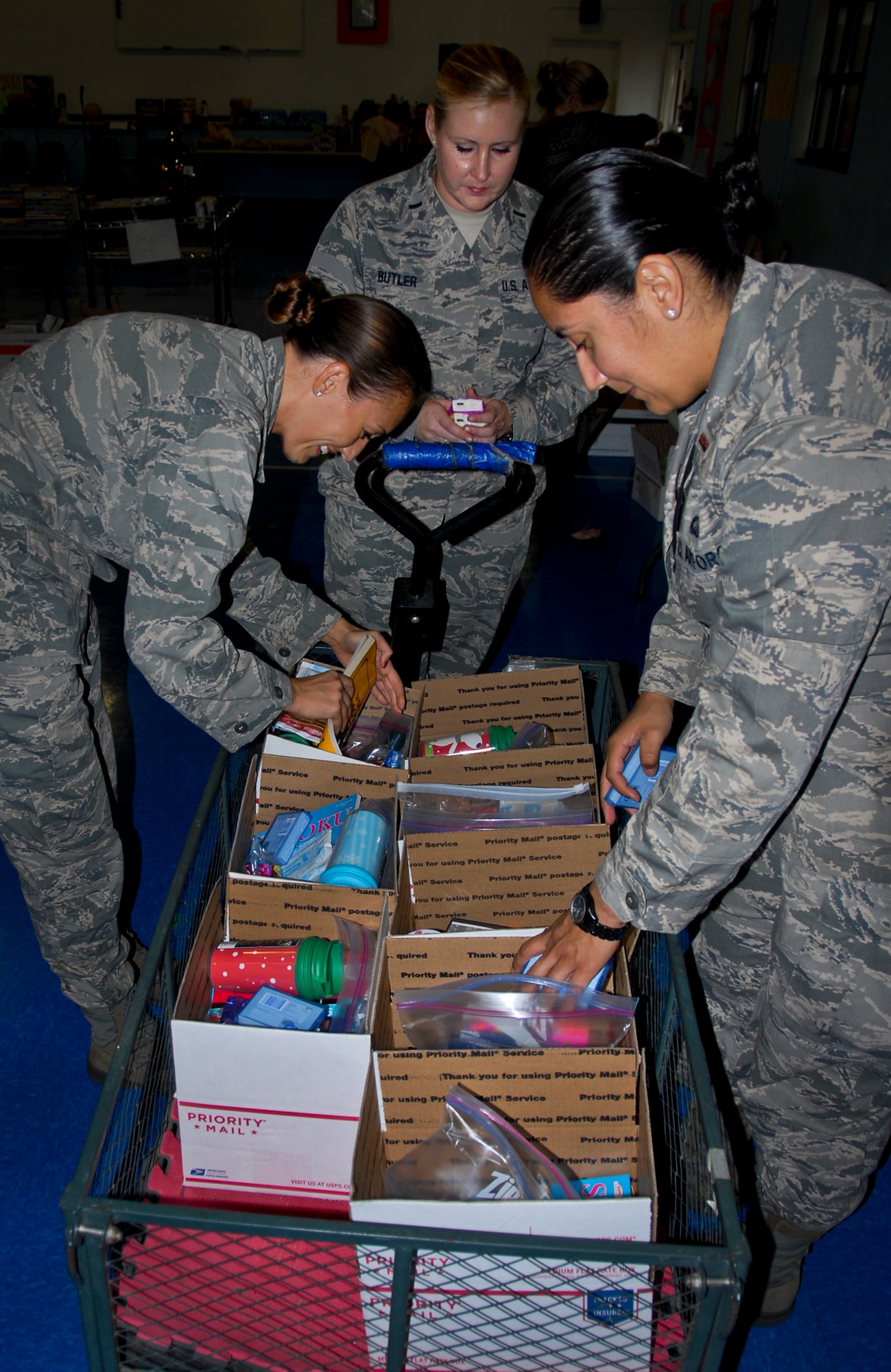 From left, Capt. Corrine Stewart, of the 96th Medical Group; 1st Lt. Jeanna Butler, of the Air Force Life Cycle Management Center; and 2nd Lt. Mikeya Ortiz, from the 86th Fighter Weapons Squadron, load various donated items into Christmas care packages at the troop care drive, at the Eglin Elementary School Gym Dec. 5. The Company Grade Officers’ Council collected more than 6,000 items and more than 1,000 handwritten Christmas cards from 12 Okaloosa County schools, area agencies and base squadrons for the packages.  Volunteers, spouses and families of Eglin’s deployed troops assisted in putting together 183 care packages for shipment overseas. The total shipment weighed 926 lbs.  (U.S. Air Force photo/Kevin Gaddie)