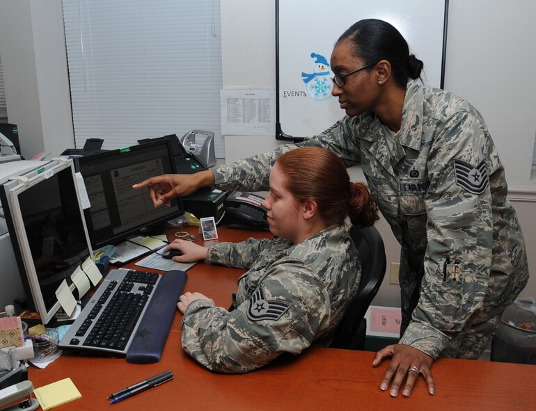 Tech. Sgt. Shanera Ruth, 2nd Force Support Squadron individual personnel readiness NCO in-charge, reviews a document with Staff Sgt. Jessica Villescas, 2nd FSS IPR craftsman, on Barksdale Air Force Base, La., Dec. 4, 2013. Ruth was selected from 1,000 NCOs across the Air Force to become a Military Training Instructor. (U.S. Air Force photo/Staff Sgt. Sean Martin)