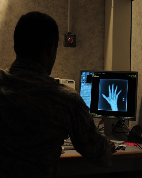 Airman 1st Class Logan Lewis, 2nd Medical Group imaging technologist, looks at a patients X-ray on Barksdale Air Force Base, La., Dec. 4, 2013. Logan is in the control panel area behind a led based wall, where he can adjust settings to the x-ray machine while also avoiding constant exposure. (U.S. Air Force photo/Senior Airman Joseph A. Pagán Jr.)
