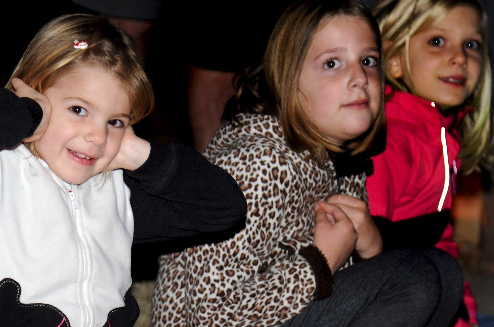 Children cover their ears and watch in anticipation as blanks are fired during the holiday parade Dec. 4, 2013, at Cannon Air Force Base, N.M. The parade included floats decorated by the squadrons and an appearance by Santa Claus himself. (U.S. Air Force photo/Airman 1st Class Chip Slack)