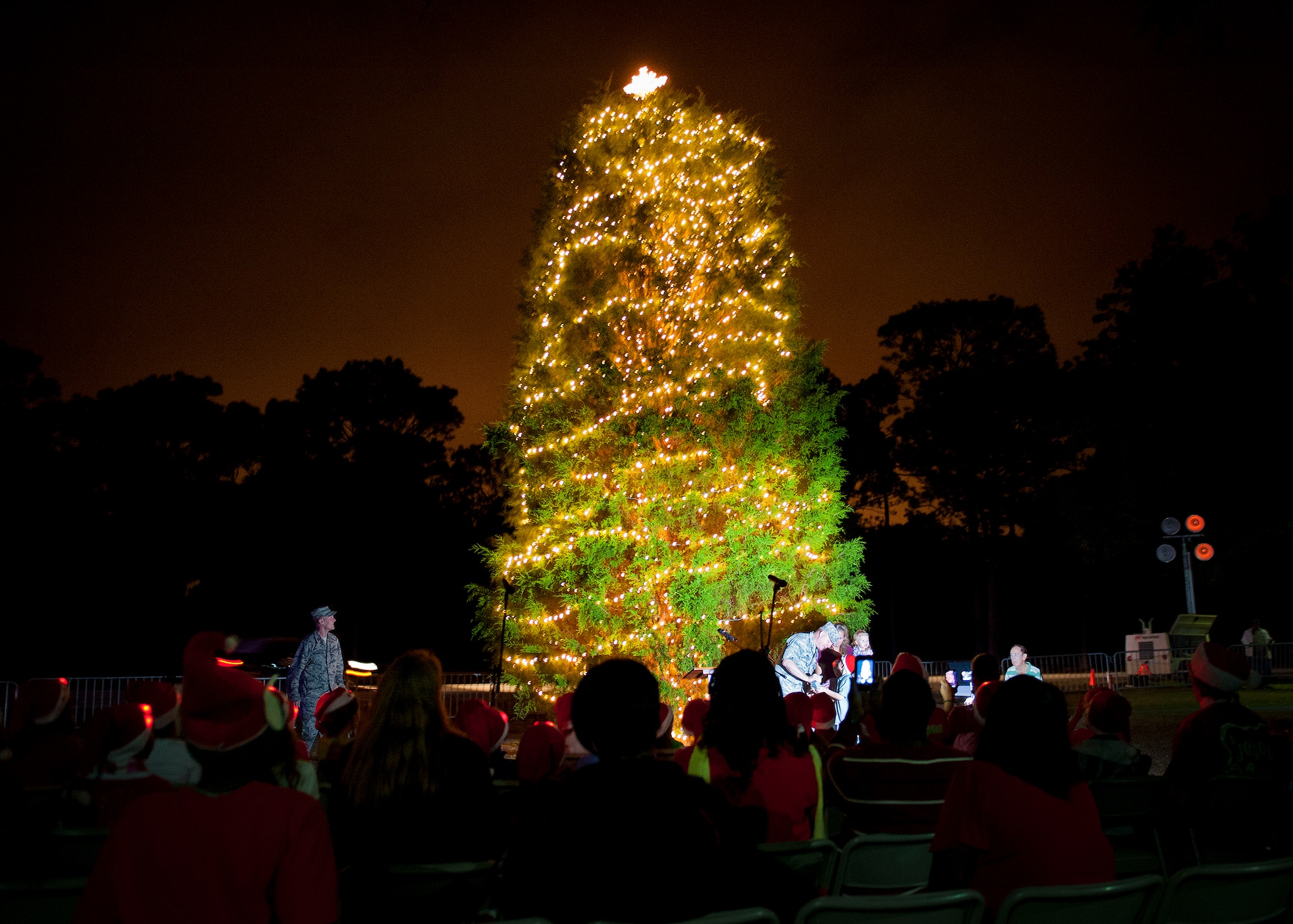 Brig. Gen. David Harris, the 96th Test Wing commander, lights up the Eglin Christmas tree with the help of the Saffo family at Team Eglin's annual Christmas tree lighting ceremony at the West Gate Chapel Dec. 6. The Saffo family was chosen for the honor because their father, Lt. Col. Clinton Saffo, is currently deployed. Chaplains and senior leadership led the event with messages of unity and awards for the base-wide, life-sized card decoration contest. Following the lighting of the tree, Santa Claus arrived by fire truck to meet with the children and hear their Christmas wishes. (U.S. Air Force photo/Sara Vidoni)