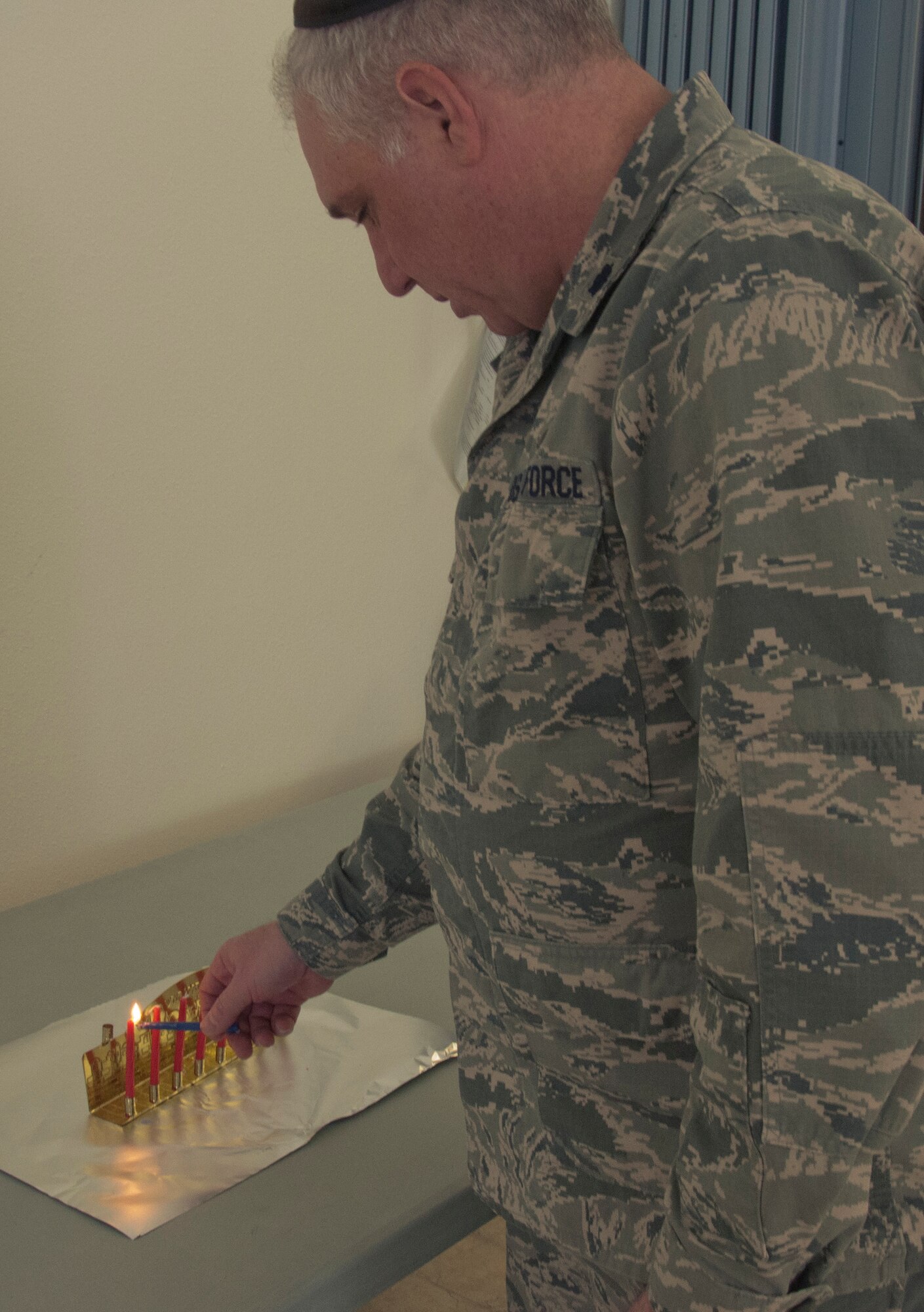131206-F-GZ967-003 Chaplain (Lt. Col.) Joshua Narrowe, 90th Missile Wing chaplain, begins lighting his menorah during an observance of the last day of Hanukkah Dec. 5. (U.S. Air Force photo by Airman 1st Class Brandon Valle)