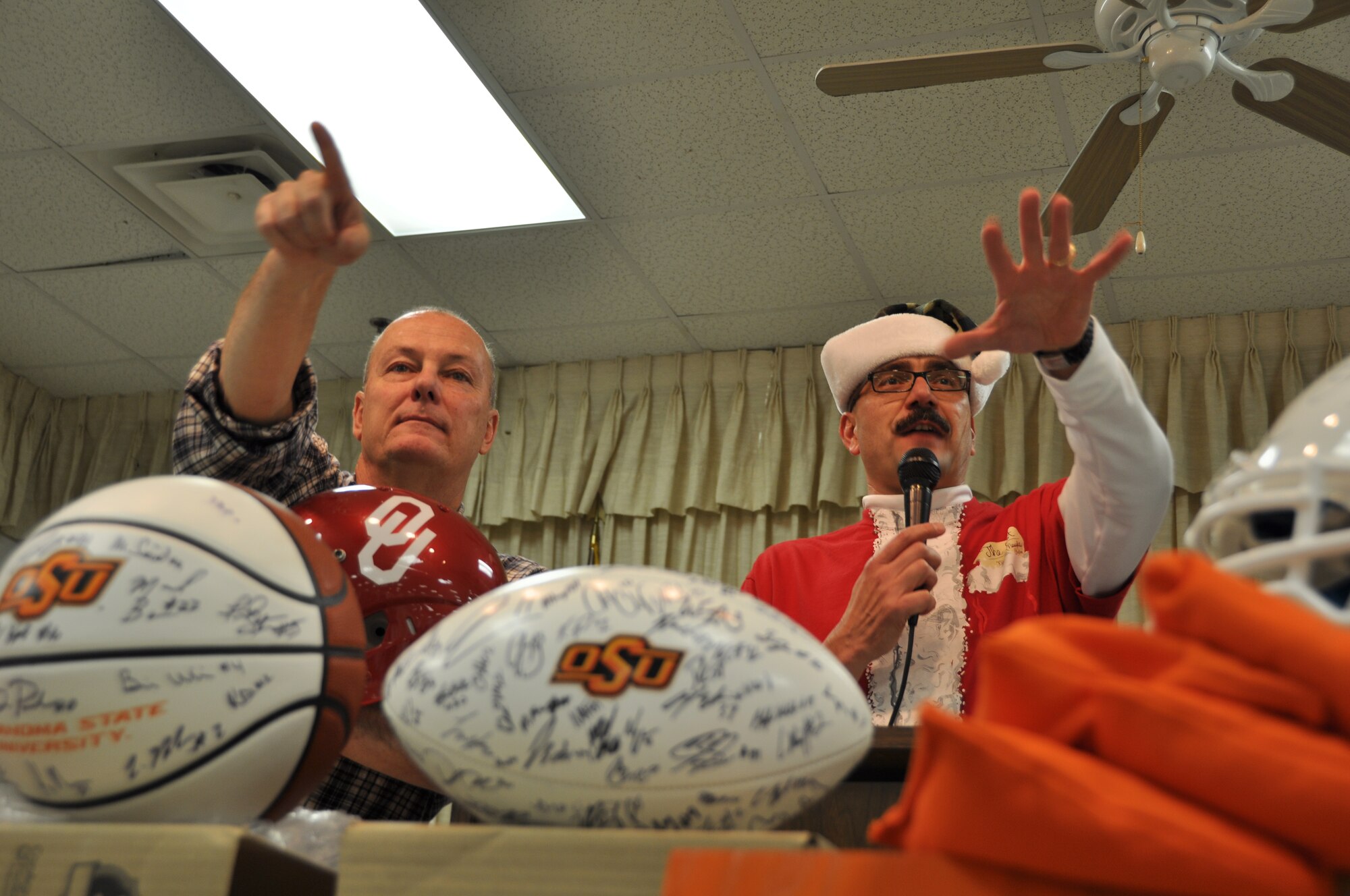 Retired Chief Master Sgt. Steven Wright and Senior Master Sgt. Bob Gaspar auction off an OU football helmet at the Operation Holiday Spirit fund-raiser at the Del City American Legion, Dec. 7. The event raised a record-breaking $34,769 to support guard and reserve Airmen in need. (U.S. Air Force Photo/Maj. Jon Quinlan)