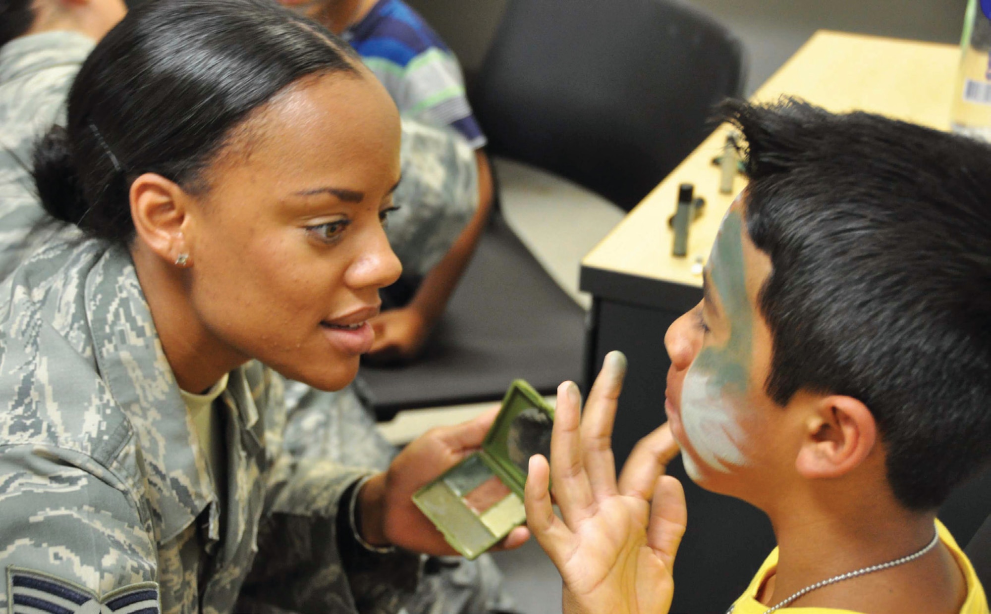 Staff Sergeant Shamera Coleman, 452nd Logistics Readiness Squadron, applies finishing touches to the camo-paint on 10-year-old Cristian Medina’s face during a mock, deployment line set up by members of the squadron. Medina was among approximately 40 children, along with their parents, that attended the first Operation Family First event put on by the squadron, with support from the 452nd Security Forces Squadron and Medical Group, the Yellow Ribbon Program, USO, and others. (U.S. Air Force photo/Staff Sgt. Joe Davidson)