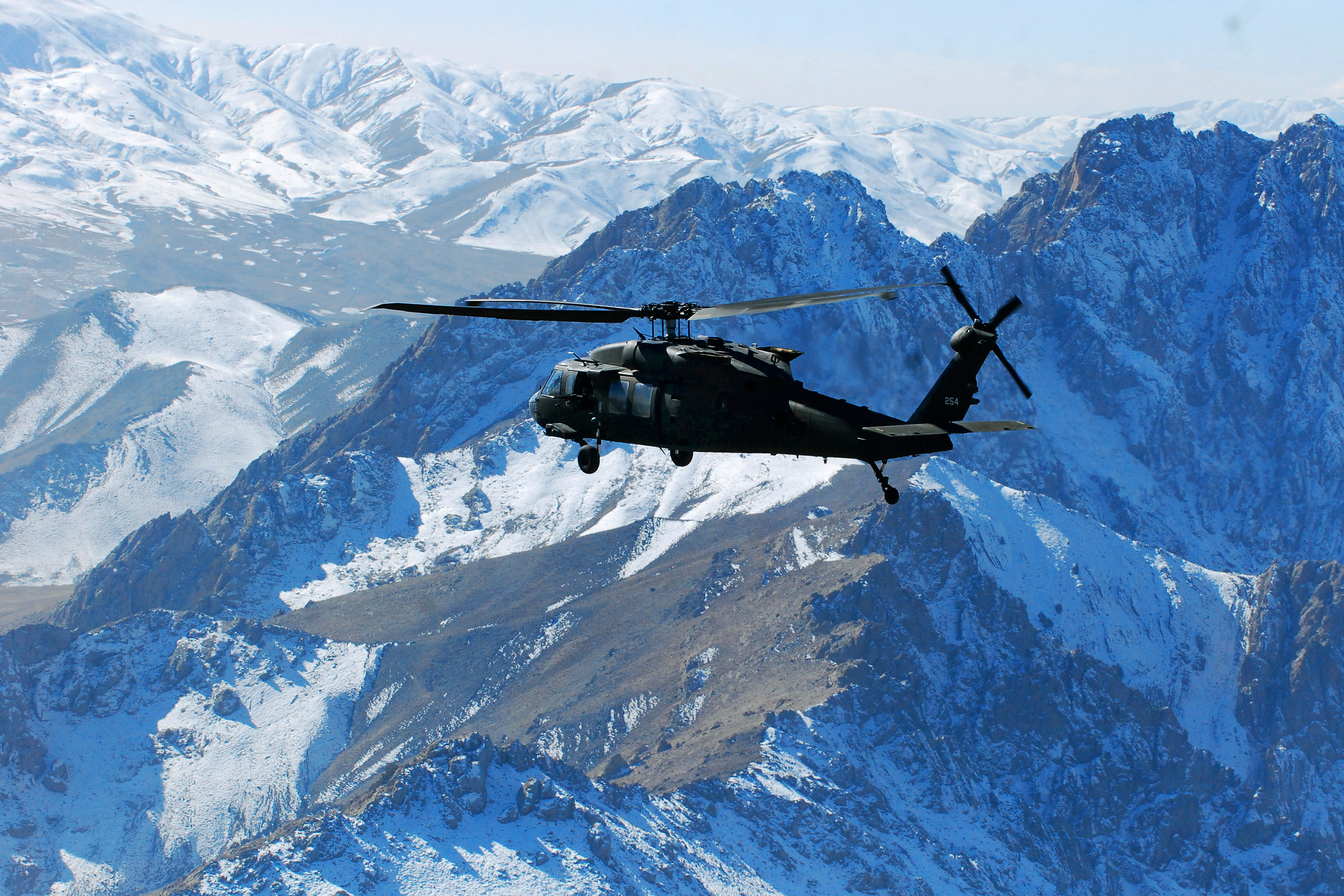A U S Army Uh 60m Black Hawk Helicopter Flies Through A Snow Dusted Mountain Pass During
