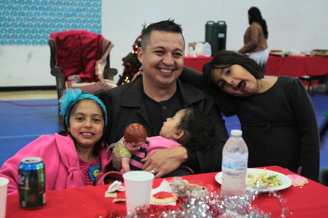 Capt. Jorge Escatell, recruiting advertising officer for 12th Marine Corps District and his daughters enjoy lunch during the 12MCD holiday party on Marine Corps Recruit Depot San Diego, Dec. 7, 2013. Calvary Chapel of Huntington Beach provided lunch for the Marines and their families. 