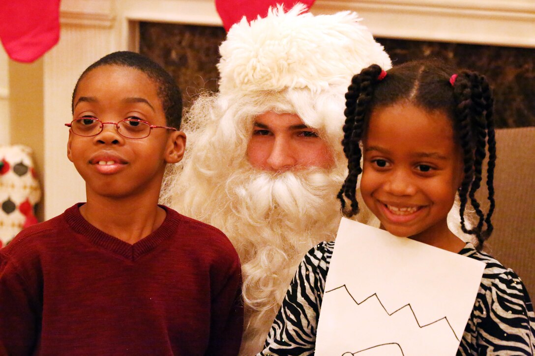 Kaweli, 8, and Amira, 5, pose for a picture with Santa during the EFMP holiday event at the Lincoln Military Housing main office Dec. 6, 2013. More than 100 people participated in the annual event