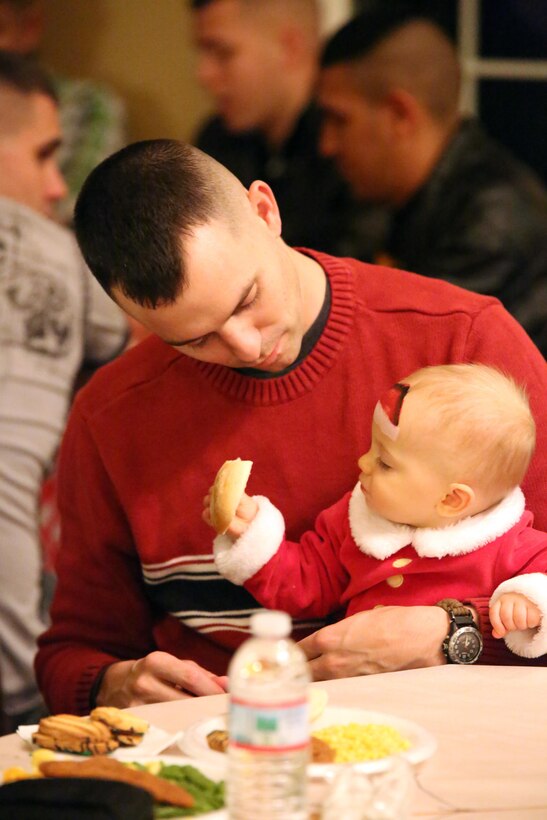 A father and son share dinner during the EFMP holiday event at the Lincoln Military Housing main office on Dec. 6, 2013. Children were able to visit with Santa and receive gifts during the event. 