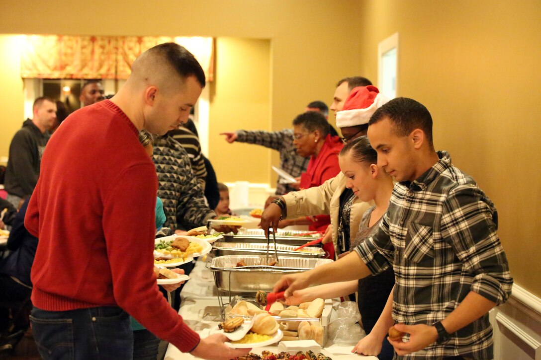Volunteers and staff serve dinner during the EFMP holiday event at the Lincoln Military Housing main office on Dec. 6, 2013. More than 100 people attended the event. 