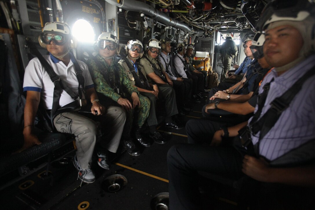 Distinguished guests look out the back of an MV-22B Osprey in flight Dec. 4 at Rimba Air Base, Brunei, during the 4th biennial Brunei Darussalam International Defense Exhibition and Conference. Government organizations and various companies at BRIDEX 13 represented approximately 70 countries. The five-day event includes displays and demonstrations of military equipment, with the theme of bridging the capability gap. BRIDEX 13 is an opportunity for communication and cooperation with regional partners and allies, builds strong multilateral relationships and enhances preparedness for disasters and other contingency operations. U.S. participation in BRIDEX 13 demonstrates cooperative engagement with Brunei and continued commitment to regional security and stability in the Asia-Pacific region. The Osprey is assigned to Marine Medium Tiltrotor Squadron 262, Marine Aircraft Group 36, 1st Marine Air Wing, III Marine Expeditionary Force. (U.S. Marine Corps photo by Cpl. Alyssa Gunton/Released)