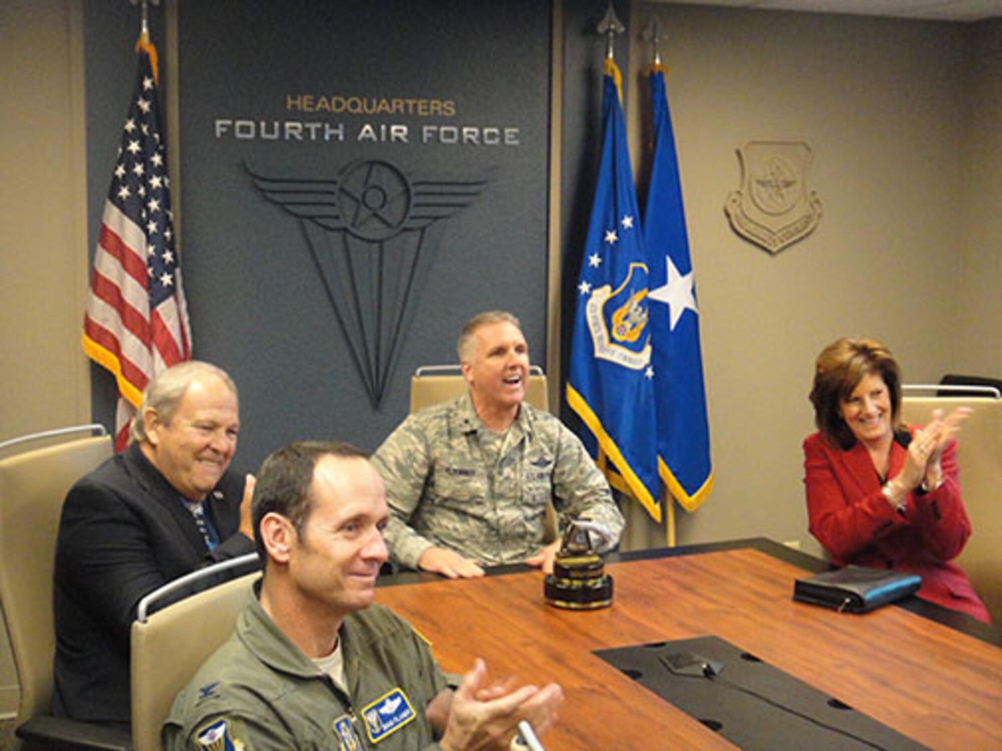 Col. Douglas Planer (foreground), 4th Air Force A3 Director, joins (from left) Roger Rupp, Riverside Military Affairs Committee Chairman; Brig. Gen. John C. Flournoy Jr., 4th Air Force Commander; and Cindy Roth, Greater Riverside Chambers of Commerce President, in congratulating the 349th Air Mobility Wing, Travis Air Force Base, Calif., for being named the best wing in 4th Air Force for 2012 and 2013 combined. Flournoy surprised the wing’s senior leadership with the announcement via teleconference on Friday, Dec. 6, 2013. (Courtesy photo)