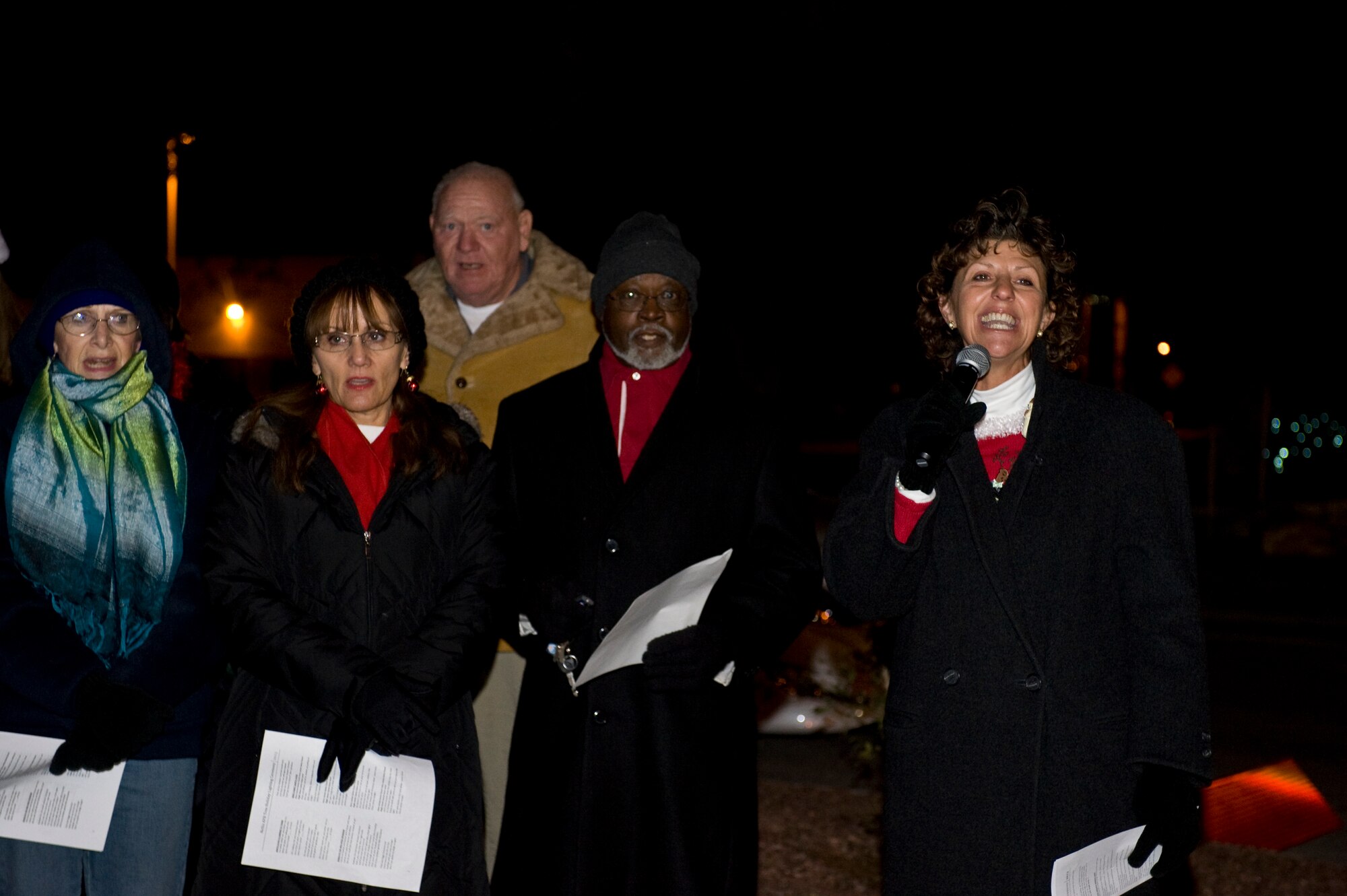 Kathy Rash, wife of U.S. Air Force Chaplain (Lt. Col.) Michael Rash, 99th Air Base Wing leads the chapel's praise service worship team in holiday song during a menorah and tree lighting ceremony Dec. 6, 2013, at Nellis Air Force Base, Nev. Approximately 100 Airmen and their families gathered outside the chapel to ring in the holiday season by singing traditional holiday songs. (U.S. Air Force photo by Airman 1st Class Christopher Tam)