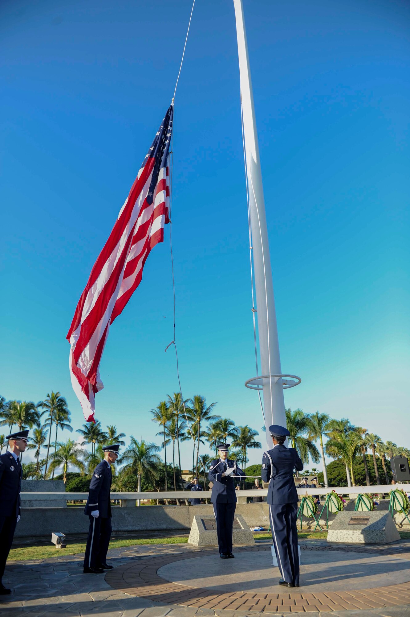 15th Wing Honor Guard members raise the U.S. flag at the December 7th Remembrance Ceremony on Hickam Field Dec. 7, 2013. The flag was flown at half- staff in honor of the 190 Airmen and civilians who lost their lives in the 1941 attack on the base.  In observance of its historical past, the ceremony took place at the flagpole in Atterbury Circle, a site which still boasts the original bullet holes and strafing marks from the attack. (U.S. Air Force photo/Staff Sgt. Terri Paden)