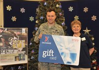 Susan Humphress store manager presents Airman 1st Class Joseph Bac, 319th Contracting Flight contracting administrator, with the National Collegiate Athletic Association “Make the Grab” sweepstakes gift card at The Exchange, Dec. 6, 2013 on Grand Forks Air Force Base, N.D. The sweepstakes grand prize consisted of $2,500 in exchange gift cards. (U.S. Air Force photo/Senior Airman Xavier Navarro)