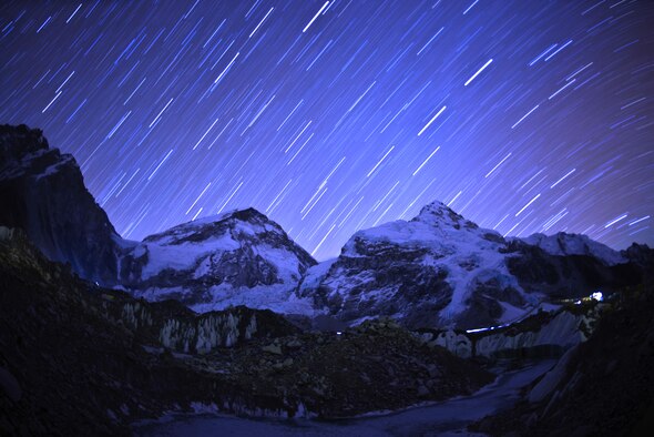 A clear night in Everest Basecamp casts a purple hue giving backdrop to the stars of Nepal May 12, 2013.  Light streaks from headlamps paint the glacier as the world spins under the celestial show. (photo by Nick Gibson)  