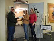 Minot Officers Spouses' Club Charitable Coordinator, Chris Corbin (left), presents a check in the amount of $500 to Betsy Barnett, Cinderella Boutique Chairperson, while Adrienne Feeney, Cinderella Boutique Co-chairperson, looks on. In keeping with the mission of the Minot Officers Spouses' Club to promote non-profit charitable, educational, cultural, and social activities within the community it serves, the MOSC made a generous donation in the amount of $500 on December 8 in support of the Cinderella Boutique. (Courtesy Photo)