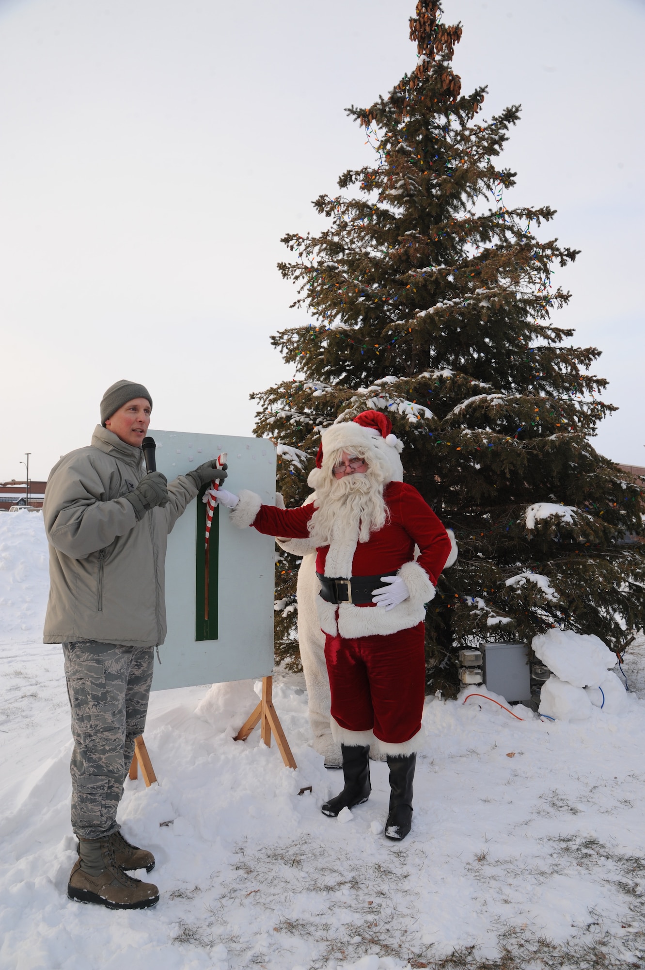 Col. Paul Bauman, 319th Air Base Wing commander, and Santa Claus pull the lever to light the base holiday tree outside of the Commissary, Dec. 5, 2013, on Grand Forks Air Force Base, N.D. The tree lighting ceremony is an annual part of celebrating the winter holiday season on Grand Forks AFB. (U.S. Air Force photo/Airman 1st Class Zachiah Roberson)