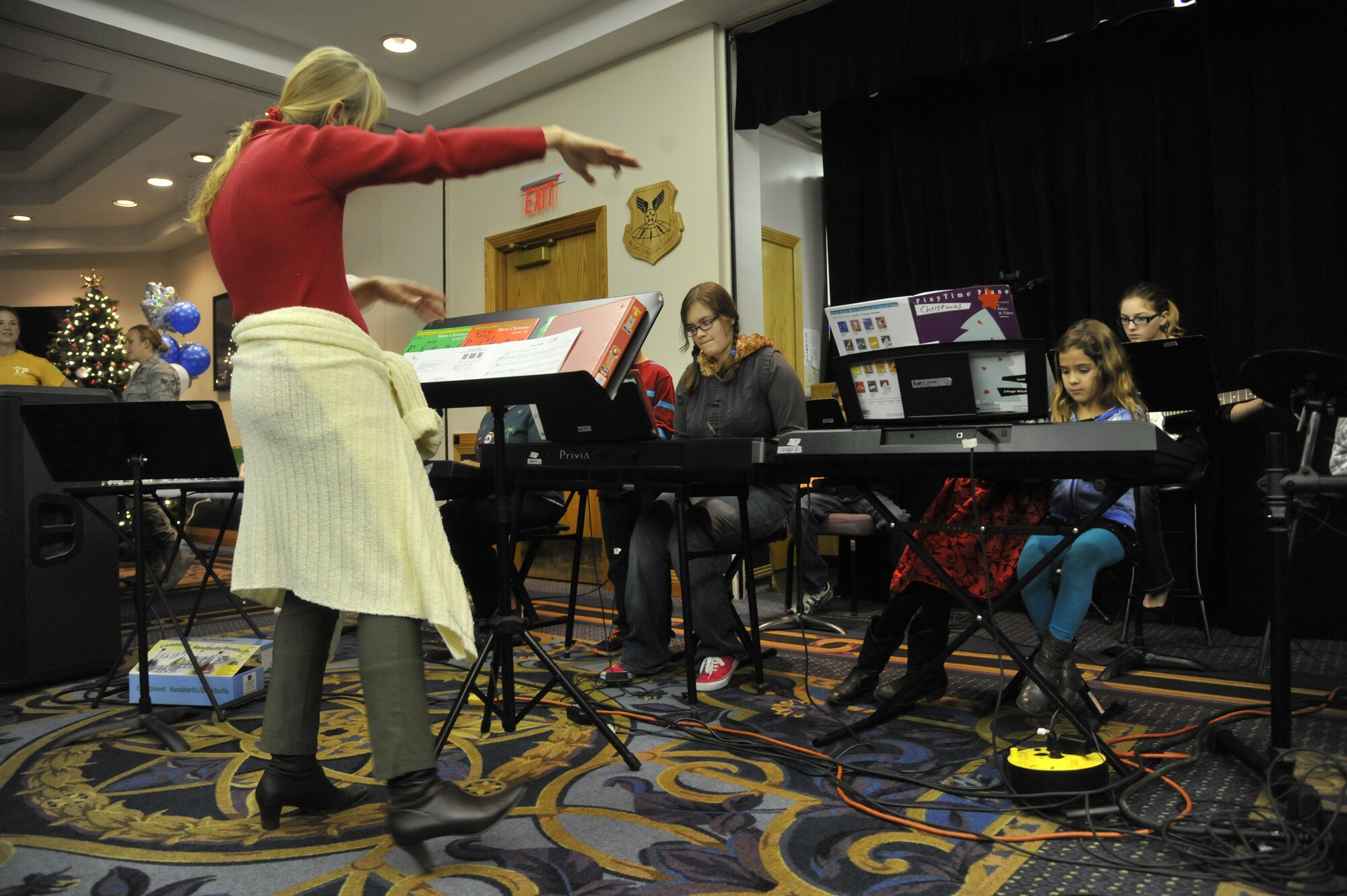 Tammy Templeton, Keys of Joy music instructor, orchestrates a children choir at Whiteman Air Force Base, Mo., Dec. 3, 2013. The choir performed Christmas songs during the tree lighting reception to spread the joy in welcoming the holiday. (U.S. Air Force photo by Airman 1st Class Keenan Berry/Released)
