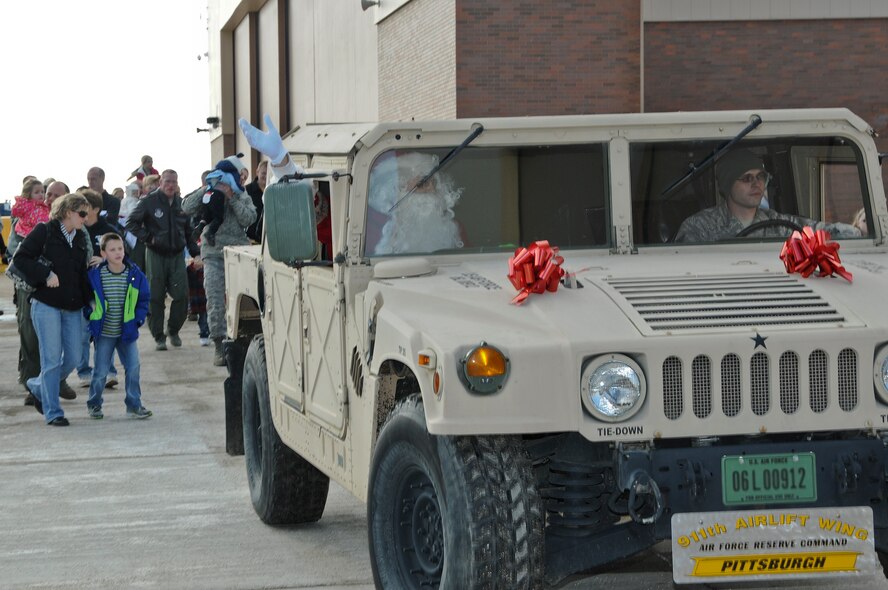 Santa waves to children while riding in a Humvee after the C-130 Hercules he was in, landed at the Pittsburgh International Airport Air Reserve Station, Dec. 7, 2013. Santa arrived at the base just in time for the 911th Airlift Wing holiday party, where he posed for photos with children of 911th AW Airmen. (U.S. Air Force photo by Senior Airman Joshua J. Seybert)